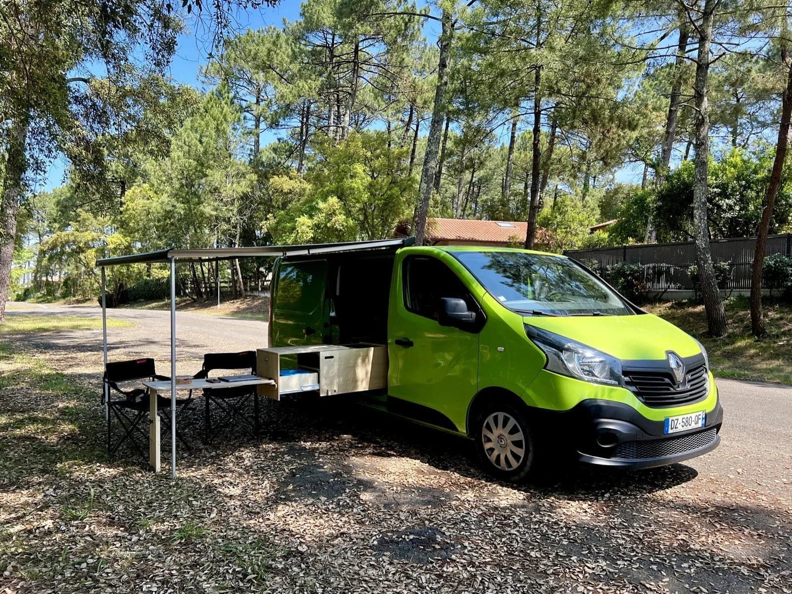 Van aménagé Vanzon Explorer auvent déployé dans une forêt de pins