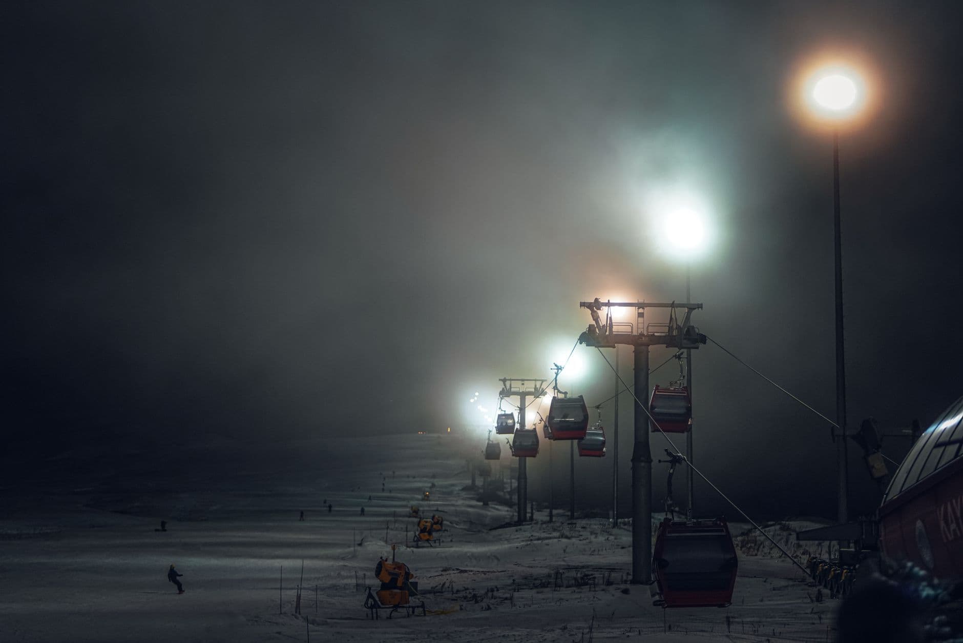 Ski lift at night amidst fog and snow, creating a serene winter scene perfect for vacation and adventure themes.