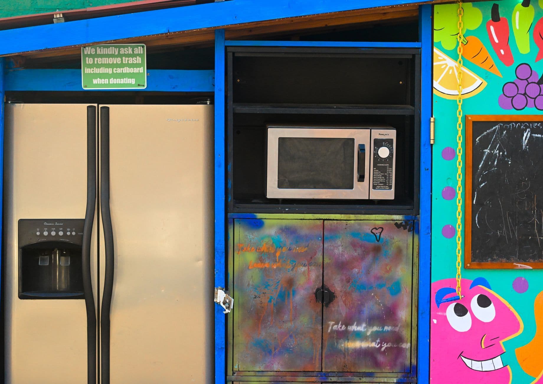 Brightly painted donation spot with a fridge, microwave, and colorful art.