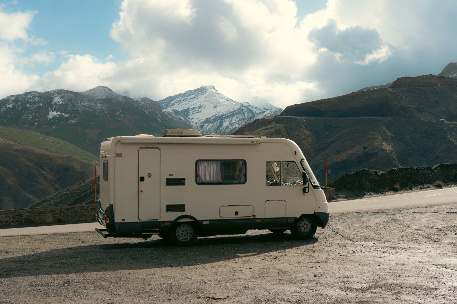 Camper van parked on roadside with stunning snowy mountain backdrop, ideal for travel and adventure themes.