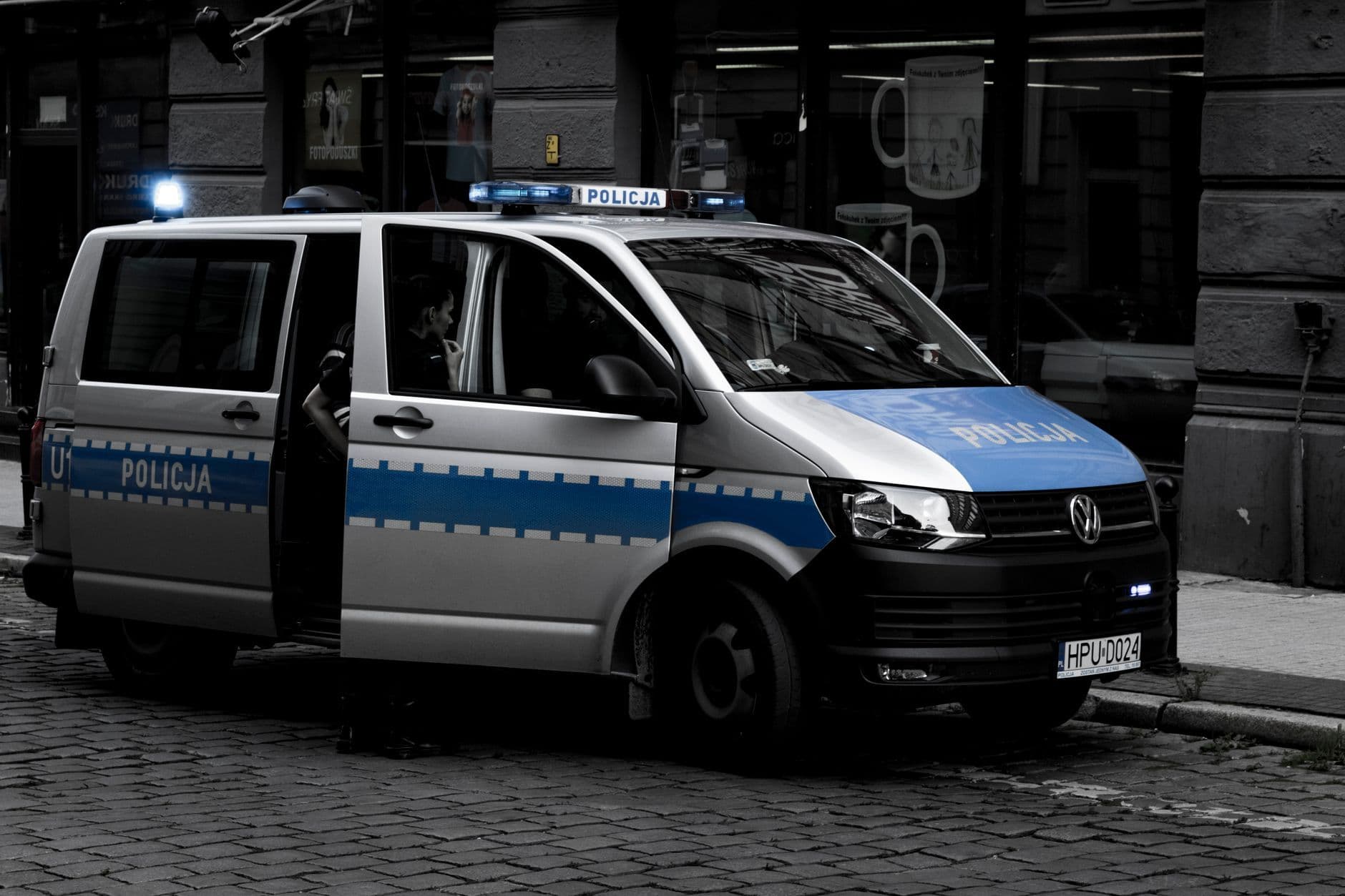 A police van parked on a cobblestone street in an urban setting.